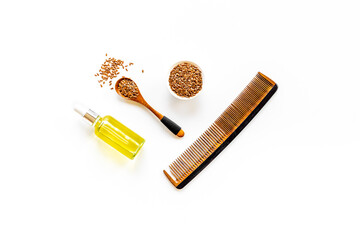 Hair treatment oil with seeds and wooden hair comb. Top view