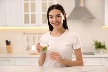 Young woman with glass of fresh lemonade at home