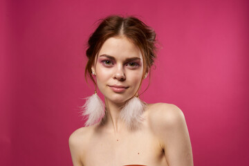 Obraz premium woman bare shoulders fluffy earrings bright makeup pink background