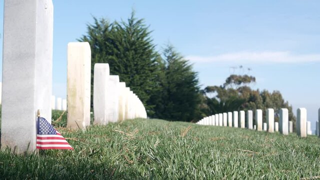 Tombstones and american flag, national memorial cemetery, military graveyard in USA. Headstones or gravestones, green grass. Respect and honor for armed forces soldiers. Veterans and Remembrance Day.