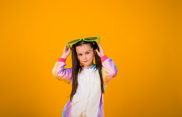 a little girl in a plush suit and big glasses on a yellow background with a place for text