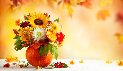 Autumn bouquet of beautiful flowers and berries in a pumpkin on wooden white table. Concept of autumn festive decoration for Thanksgiving day.