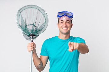 young handsome man pointing at camera choosing you with goggles and fishing net - Powered by Adobe