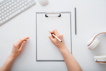 Woman writing on empty list in notepad to do list. Female hands do sketching on paper tablet in office workplace. Female hand write in notebook at work desk on white table. Top view
