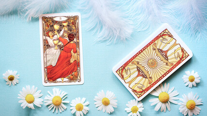 Golden tarot cards on the Blue background with Daisy flowers, three of cups