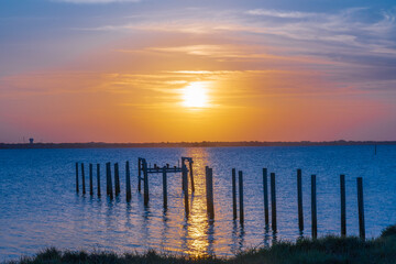 View of a yellow sunset over Indian River, Florida from the A1A. Wooden pillars of the old pier near the coast as a typical view of Florida
