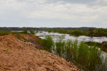 View of the lake water among the sand dunes on a cloudy summer or spring day