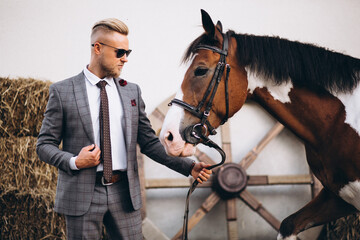 Handsome man in suit at ranch by horse