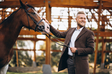 Handsome man in suit at ranch by horse - obrazy, fototapety, plakaty