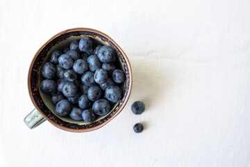 Fragrant fresh blueberries in a cup on the table, top view.