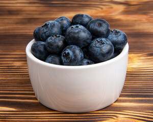 Fresh blueberry in white dish on wooden background