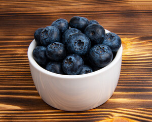 Fresh blueberry in white dish on wooden background