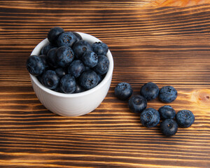 Fresh blueberry in white dish on wooden background