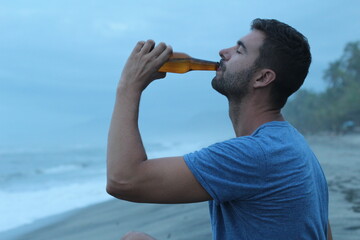 Handsome man drinking a beer in tropical beach