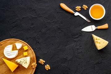 Set of cheese on wooden board with cheese knives, top view