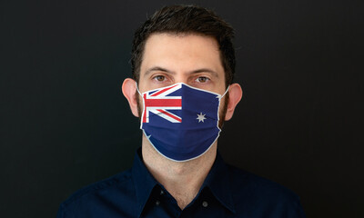 Man wearing Australian flag protective medical face mask. He looks worried and concerned. Coronavirus concept in Australia with black background.