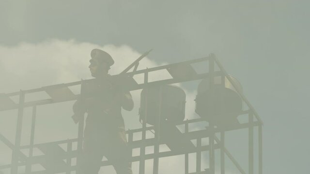 Security , guard , policeman stay in watch tower and looking arround with not licensed decorative uniform and weapon . Silhouette of guard tower or prison tower with security man . Slow Motion . 