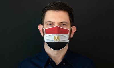 Man wearing Egyptian flag protective medical face mask. He looks worried and concerned. Coronavirus concept in Egypt with black background.