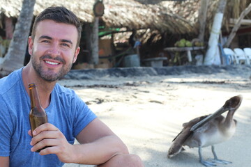 Handsome man drinking a beer in tropical beach 