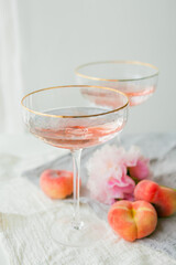 Beautiful glass with pink champagne, peaches on the background. Peonies. Aesthetic.