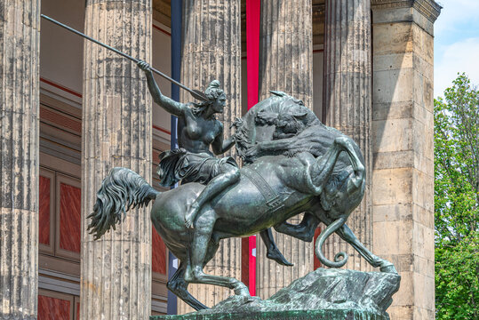 View over ancient Roman statue of beautiful young Amazonian woman rider with spear on horse being attacked by lion at Altes History Museum in historical downtown in Berlin, Germany