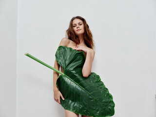 red-haired woman covers naked body with palm leaf exotic