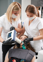 Doctors using portable dental x-ray machine while examining patient teeth in dental office, performing intraoral scanning with modern equipment. Concept of digital dentistry and intraoral radiography. © anatoliy_gleb