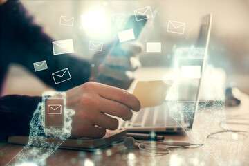 Double exposure of man's hands holding and using a digital device and envelop hologram drawing. E-mail concept.