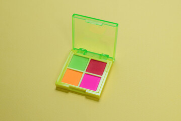 Purple, green, orange and blue eye shadow palette on a green background. Make up. Neon colours.