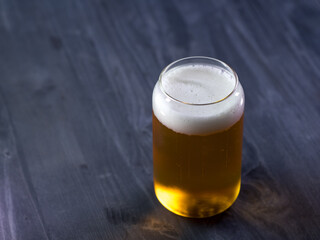 A glass of light beer on a black wooden table copy space