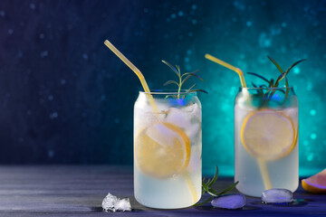 Beautiful cold cocktails with lemon and rosemary. Gin and tonic in a glass. Bright color lighting, bar menu copy space