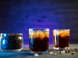 Two cold cold brew coffees on a black table, neon lighting
