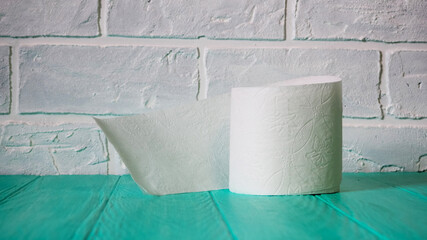 A roll of toilet paper on a blue wooden background. White paper texture background. Top view.