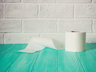 A roll of toilet paper on a blue wooden background. White paper texture background. Top view.