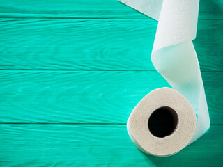 A roll of toilet paper on a blue wooden background. White paper texture background. Top view.