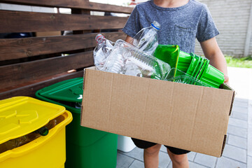 The boy collect the plastic trash into the paper box for recycling
