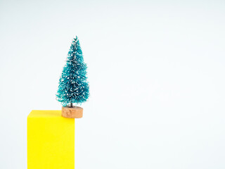 Gift card with green small toy christmas tree on yellow figure for concept design. House decoration.