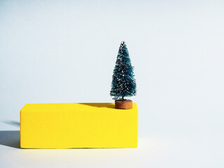 Gift card with green small toy christmas tree on yellow figure for concept design. House decoration.