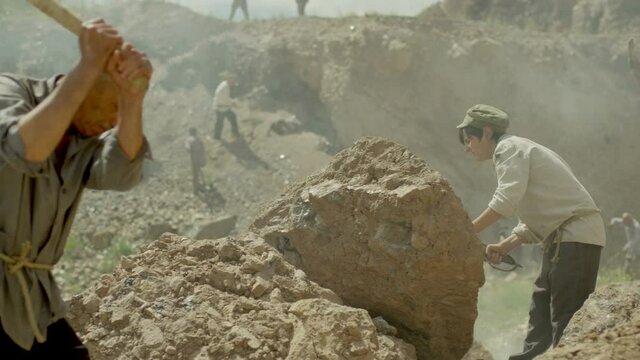 Young miner boy is working in a quarry . Group of many workers are mining with pickaxe in a quarry . Scenic shot in vintage style with artists . Shot on RED EPIC Cinema Camera in slow motion.