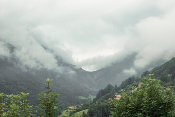 View of houses in the mountains with forests in the fog in Entremont, Haute-Savoie, France
