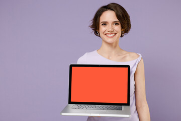 Young smiling freelancer copywriter happy woman 20s wearing white t-shirt hold use work on laptop pc computer with blank screen workspace area isolated on pastel purple background studio portrait