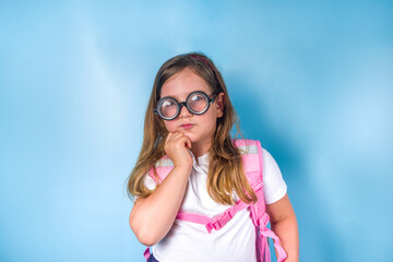 Back to school concept. School invitation, advertisement banner. Cute primary student schoolgirl in white blue classic uniform, with books backpack, funny glasses. Colorful blue background copy space