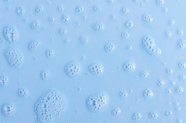 Foam drops on a blue background close-up. The texture of water and foam on a colored background
