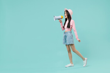 Full size body length side view young brunette asian woman 20s wears pink clothes hold scream in megaphone announces discounts sale Hurry up isolated on pastel blue color background studio portrait