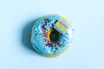 A donut with blue icing on a blue background. A sweet donut on a light background of the kopi space