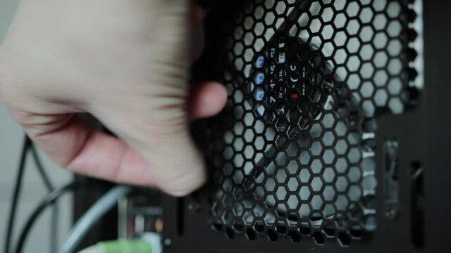 A computer repair and maintenance technician unscrews the cooler of the power supply unit to cheat and replace it, close-up. Computer service, technology