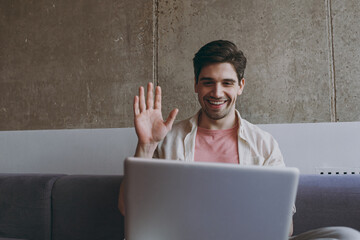 Young pensive man in casual clothes beige shirt use laptop pc computer work online talk by video...