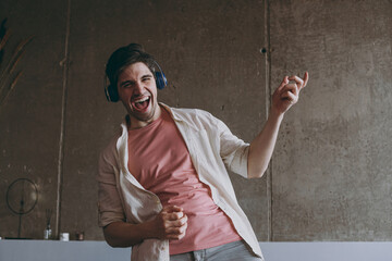 Young expressive singer fun joyful happy overjoyed man wear casual clothes beige shirt pink t-shirt...