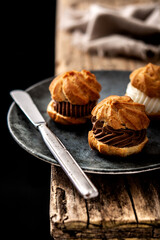 chocolate and cream profiteroles on rustic wooden table