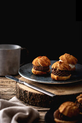 chocolate and cream profiteroles on rustic wooden table
